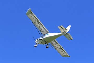 	
Ultralight airplane flying in a blue sky