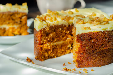 Sliced carrot cake filled and topped with cream cheese buttercream and decorated with walnuts