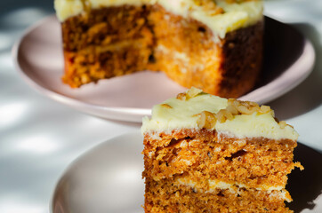 Sliced carrot cake filled and topped with cream cheese buttercream and decorated with walnuts