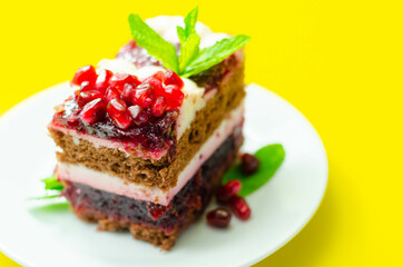 Colorful multi-layered cream chocolate cake with cherry jam and pomegranate