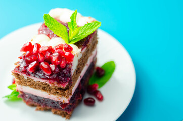 Colorful multi-layered cream chocolate cake with cherry jam and pomegranate