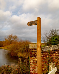 Wooden public footpath sign indicating public access along the bank of the River Bure in the Norfolk village of Buxton