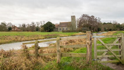 A wooden fence and gate securing entry and exit to the public footpath along the River Bure in the Norfolk village of Buxton. Captured during the winter