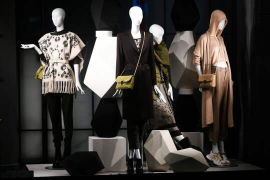 Mannequins standing in a window display of a clothing store.