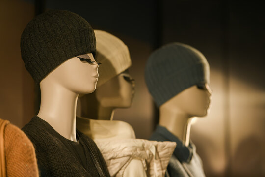 Mannequins standing in a window display of a clothing store.