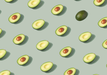Avocado halves arranged on a pastel green background. Healthy food minimal pattern