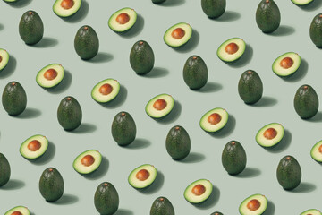 Whole and cut avocado pattern on a light green background. Vegan diet minimal flat lay