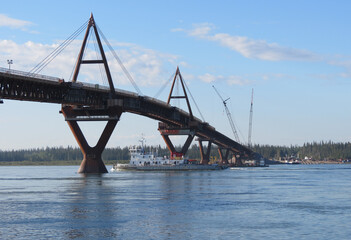 Fototapeta premium Push tug sailing under the Deh Cho Bridge