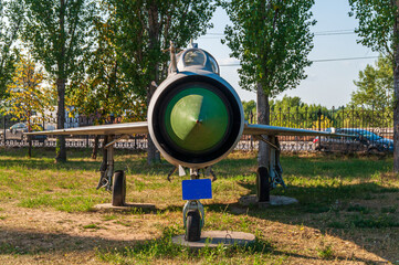 Supersonic aircraft MIG 21. Combat fighter installed in the Victory Park of Nizhny Novgorod on the ground, surrounded by trees and against the sky. High quality photo