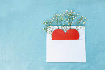 card in the form of a red heart and flowers in a white envelope on a textured blue background. Selective focus.
Message and congratulations on Valentine's Day. Valentine's Day greeting cards.
