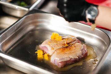 The cook is finished pouring the oil on the two slices of meat.