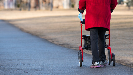 Handicapped elderly senior citizen pushing a walker on a park path. Walking and healthy lifestyle...