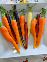 Organic multicolored carrots on a white plate.  