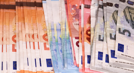 Close up of numerous euro banknotes lying on top of each other.