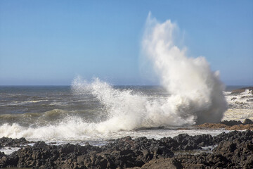 Fototapeta na wymiar An original nature photograph of giant waves crashing against a rocky shoreline 