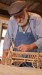 Rentner repariert in seiner Werkstatt einen alten Holzwagen Spielzeug. Hobby eines alten Mannes mit...