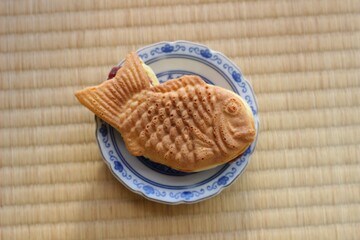 畳の上に置いてある、お皿の上にある美味しそうなたい焼き。日本の伝統的なワッフルスナック。