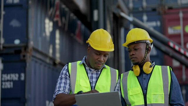 Factory African workers holding laptop and checking on site container logistic. Group of Diversity factory worker people meeting in warehouse. portrait working life in industry of logistic shipping.