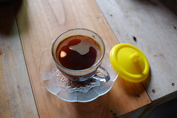 Black coffee in classic transparent cup served on the table.