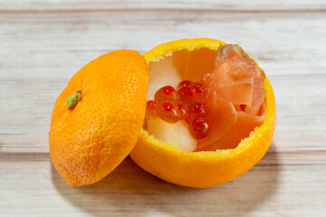 Salmon flesh and roe with turnip pickles served in a mandarin orange container as festive food for...