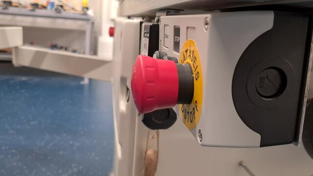 Person press on red button on side of industrial equipment, side static shot