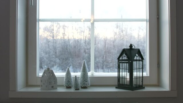 Beautiful Christmas house candle stand decoration with smoking chimney. Frozen snowy landscape outside