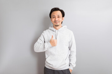 Fototapeta na wymiar Adult Asian Man in hoodie Wear eyeglasses and Pointing Finger on Gray Background.