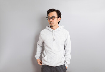 Fototapeta premium Asian adult man wearing hoodie with eyeglasses standing on grey background.
