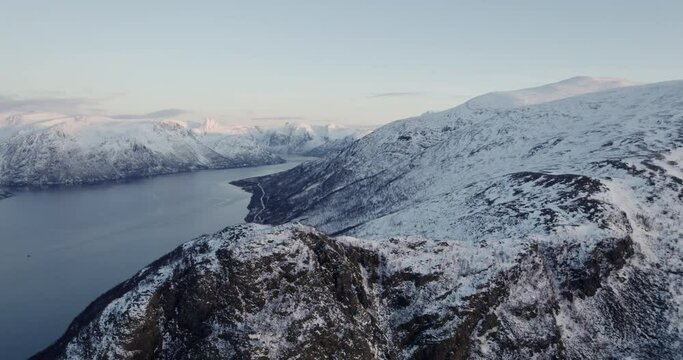 Aerial view of snow capped mountain range in norwegian fjord at sunrise