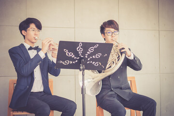 Young musician team playing trumpet and horn in music room. © Pornnarong
