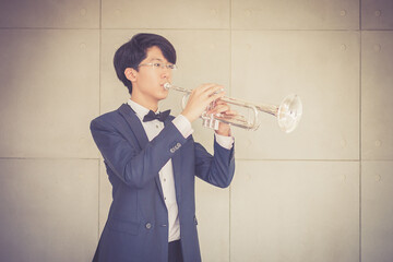 Portrait of young musician with suit form playing trumpet in music room.