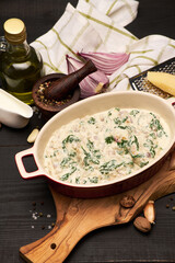Delicious meatballs with spinach in a creamy sauce in baking dish