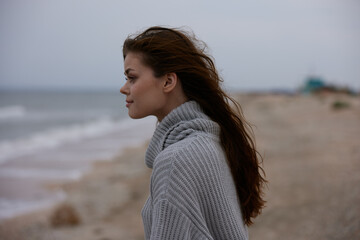 portrait of a woman in a sweater flying hair by the ocean tourism Lifestyle