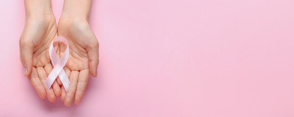 Female hands with pink ribbon on color background with space for text. Breast cancer concept