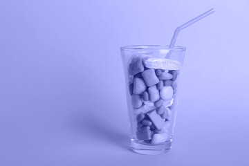Glass with different chewing gums on violet background