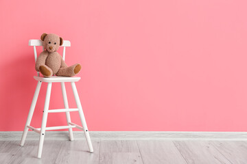 Modern chair with toy bear near color wall