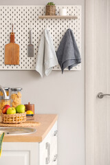 Peg board with kitchenware hanging on light wall