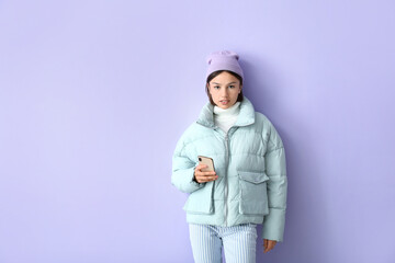 Pretty young woman in stylish warm clothes and with phone on color background
