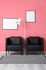 Modern black armchair, standing lamp and blank frames hanging on pink wall
