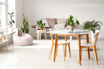 Interior of light living room with table, chairs and houseplants
