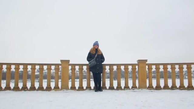 Happy woman looking at camera winter outdoors push out backward camera movement