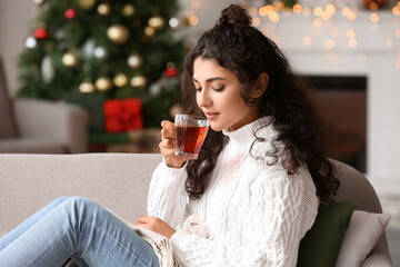 Beautiful woman drinking tea at home on Christmas eve