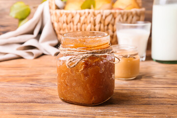 Glass jar of tasty pear jam on wooden table, closeup