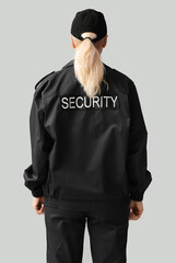 Female security guard on grey background, back view