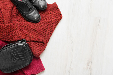 Stylish female clothes, shoes and bag on light wooden background