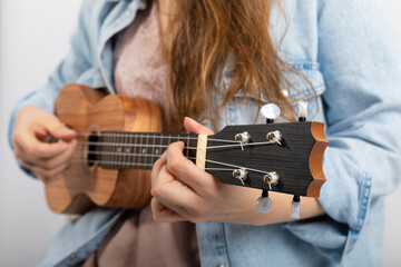 Hand of girl playing ukulele, small stringed instrument