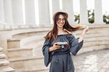 Pretty woman tourist with a camera in the city. Travel concept