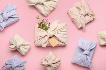 Many gift boxes wrapped in fabric on pink background