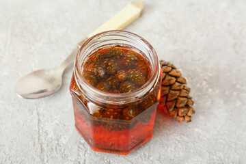 Jar of tasty pine cone jam on light background, closeup