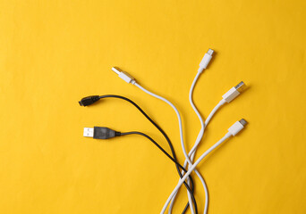 Different usb cables on yellow background. Top view